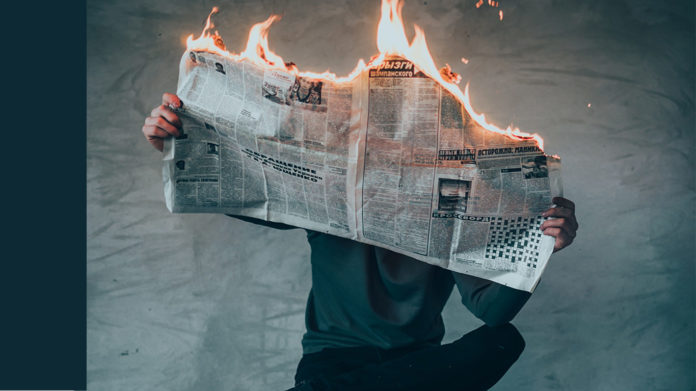 A man reads a flaming newspaper.